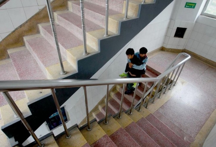 xie lleva en la espalda a su amigo zhang mientras bajan las escaleras de su escuela