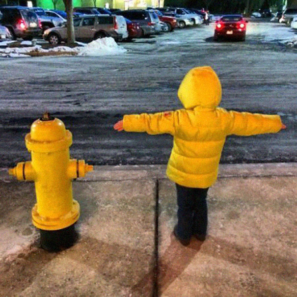 niño posando al lado de un mojón de agua