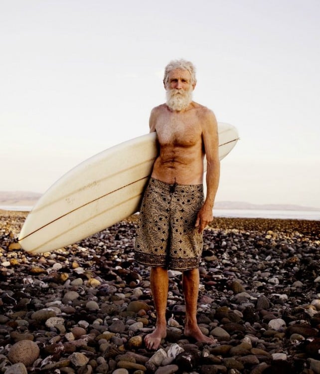 abuelo surfeando en playa llena de piedras