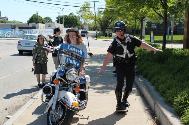 policia usando patineta al lado de un adolecente