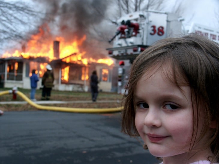 niña con los bomberros e incendio de fondo