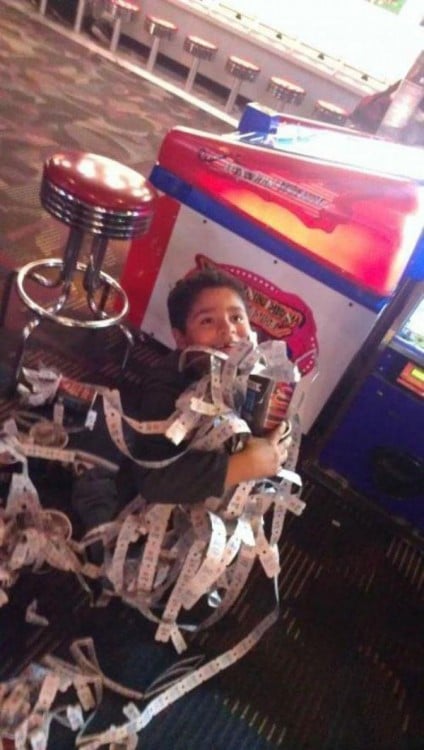 niño feliz de haber ganado infinidad de tickets en su maquina favorita