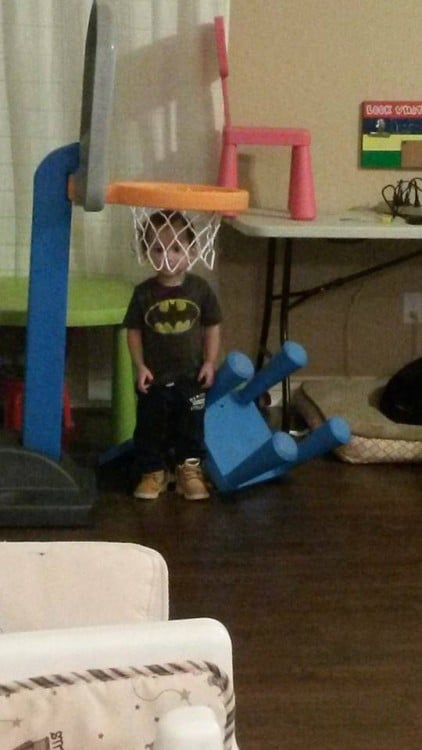niño en una habitación de juegos dentro de una canasta de basketbol 