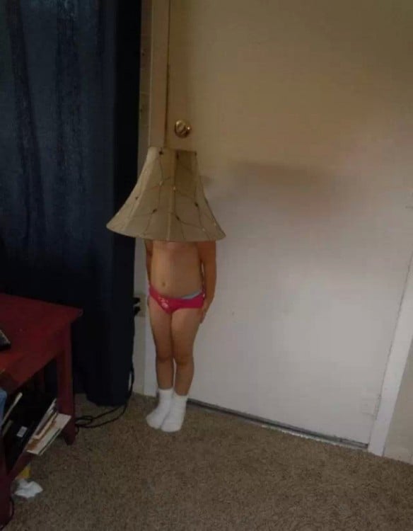 niña en ropa interior con una lampara en la cabeza frente a una puerta 