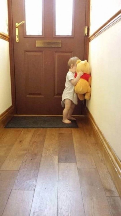 niña frente a la puerta de una casa con un peluche de winnie pooh