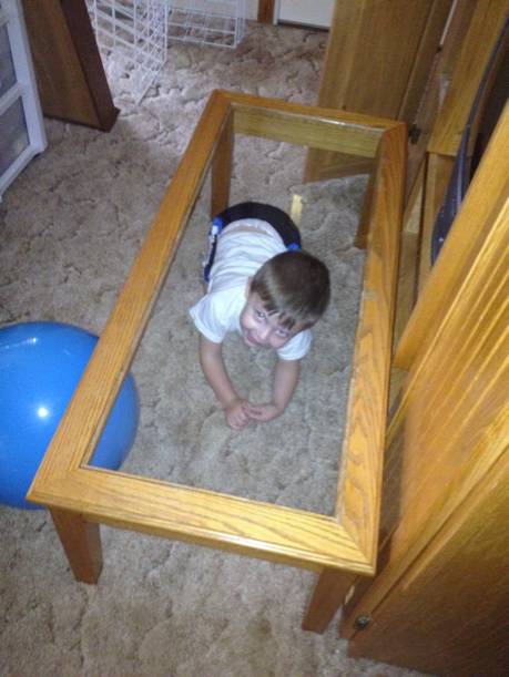 Niño escondido debajo de una mesa en la sala de una casa 