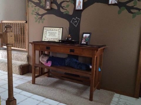 una niña acostada en medio de un mueble en la sala de una casa 