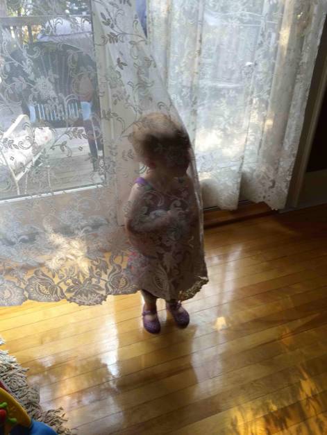 niña parada detrás de una cortina 