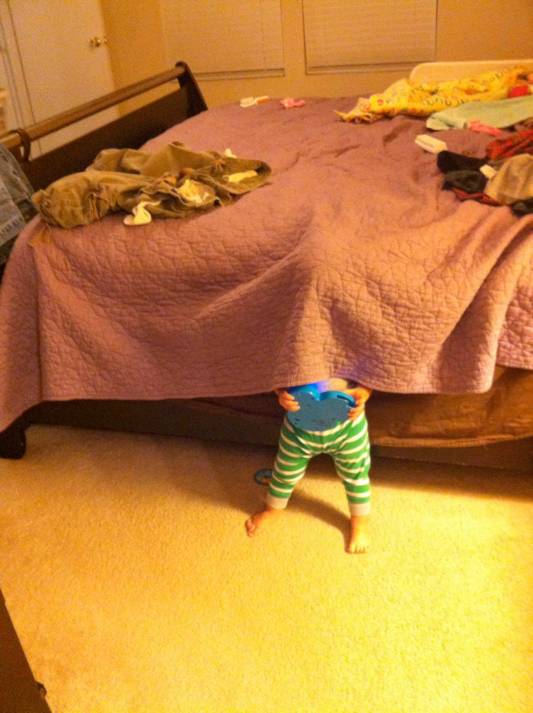 un bebé escondido debajo de la colcha de una cama 