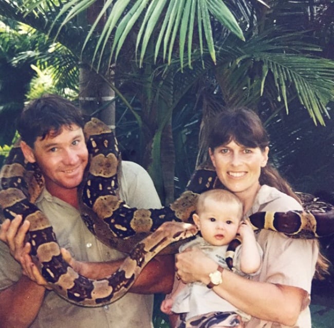 Bindi Irwin de bebé junto a su padre Steve Irwin y su madre rodeados por una serpiente 