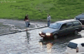 Gif de un carro arrastrando a un chico en una calle llena de agua 