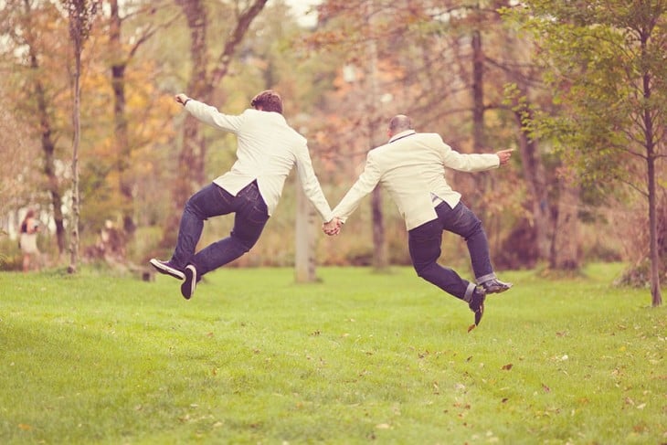 Dos chicos casados agarrados de la mano brincando juntos 