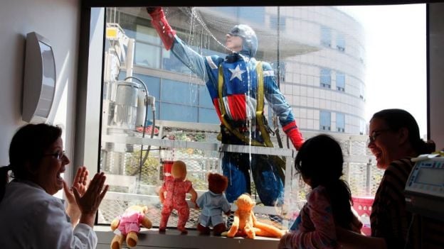 niños en el hospital asomandose por la ventana para ver a sus super heroes