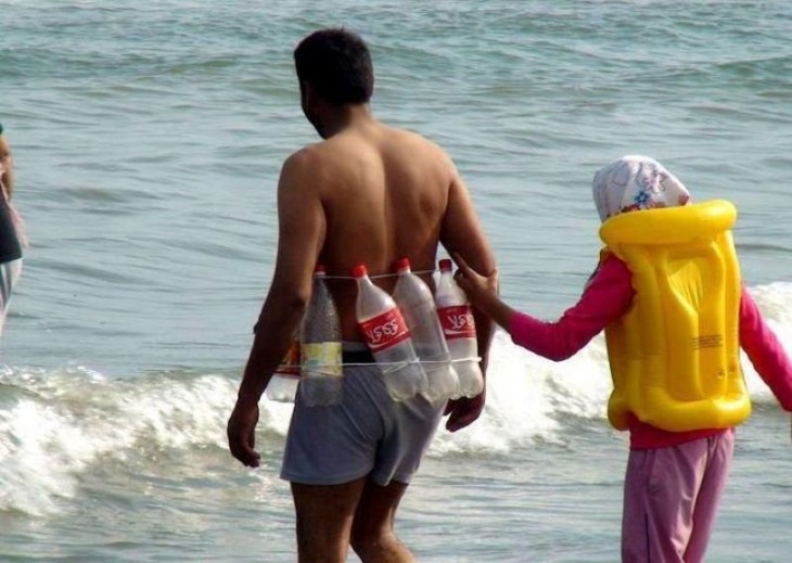 Niña sostenida del brazo de un hombre que lleva un chaleco hecho con botellas de refresco 