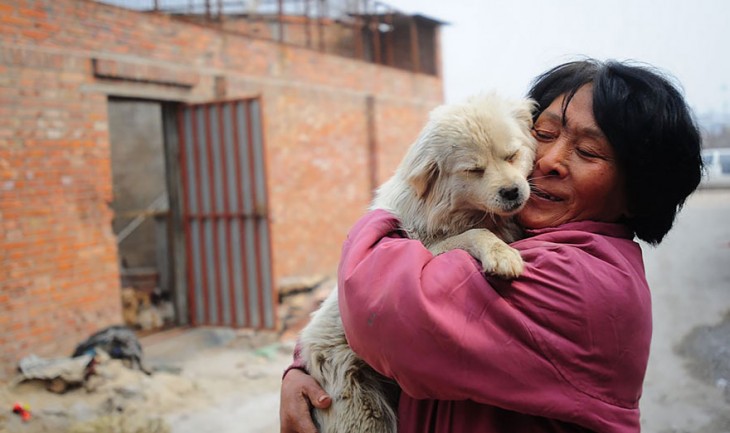 Una mujer en China abrazando a un perro que tiene en sus brazos 