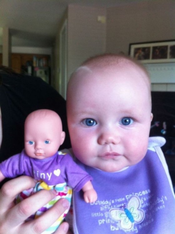 una bebé junto a su pequeña muñeca vestida igual a ella 
