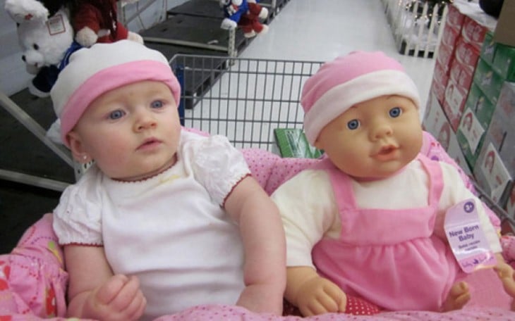 una bebé junto a su muñeca en el carrito de super mercado 