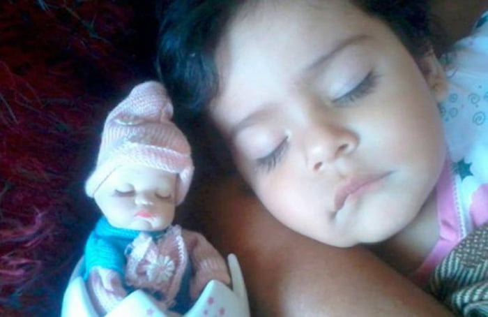 niña dormida junto a una muñeca parecida a ella 
