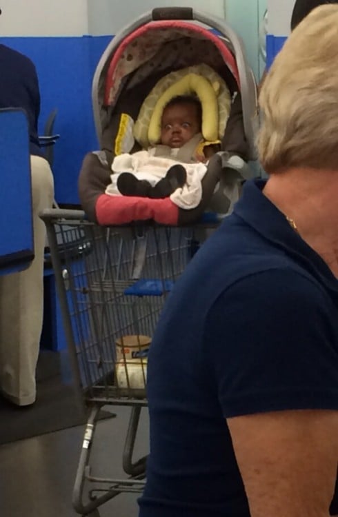Niño dentro de un porta bebé sobre un carrito del super mercado 