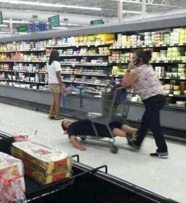 Un niño acostado en la parrilla debajo del carrito del super mercado 