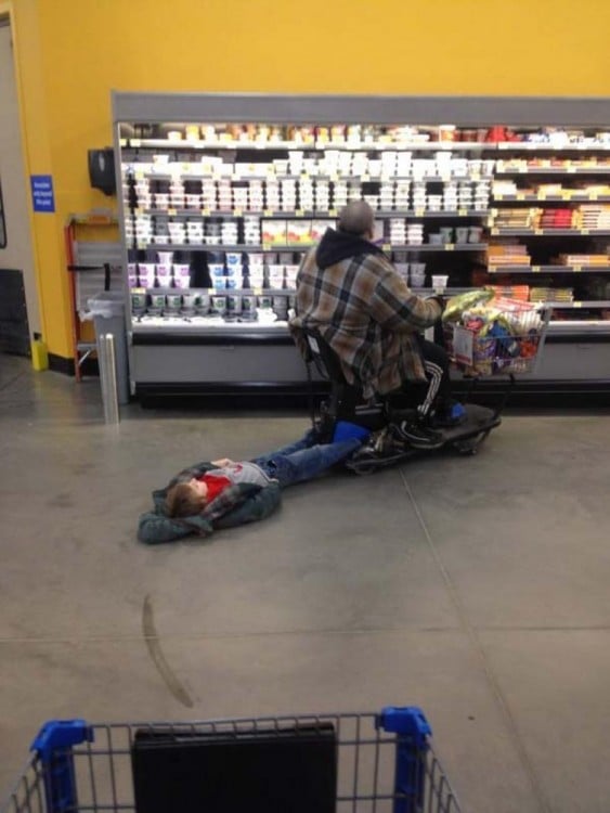 Niño que esta siendo arrastrado por el carrito de su abuelo en el centro comercial 