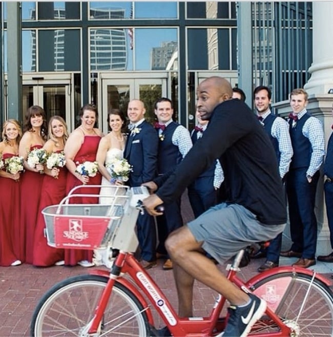 Chico en bicicleta atravesando en medio de una sesión de fotos de una boda 