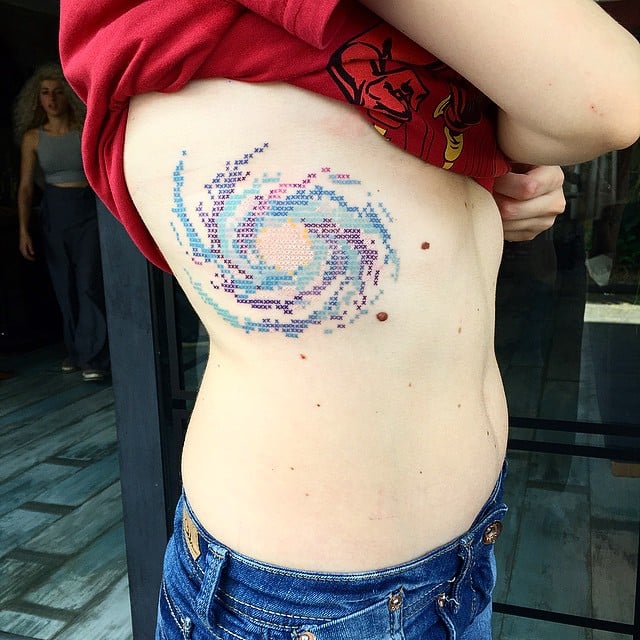tatuaje en forma de una galaxia en el costado del cuerpo de una persona 