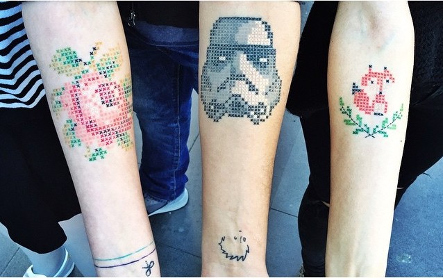 Tatuajes en forma de cruz con la figura de una rosa, Darth Vader y un zorro en los brazos de personas 