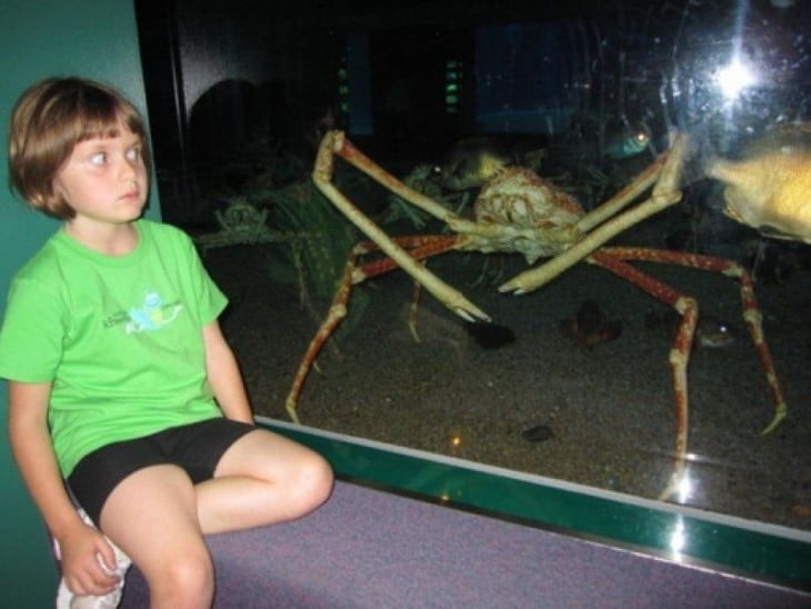 niño posando asustado con un cangrejo de centella