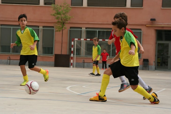 Niños en el patio de una escuela jugando fútbol 