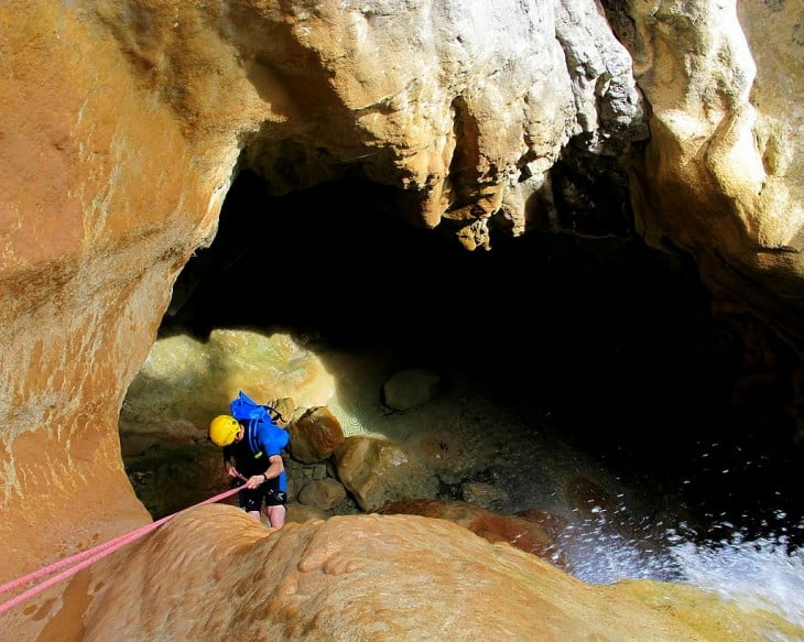 Chico haciendo Rápel en la cueva del barranco de Arandari, España 