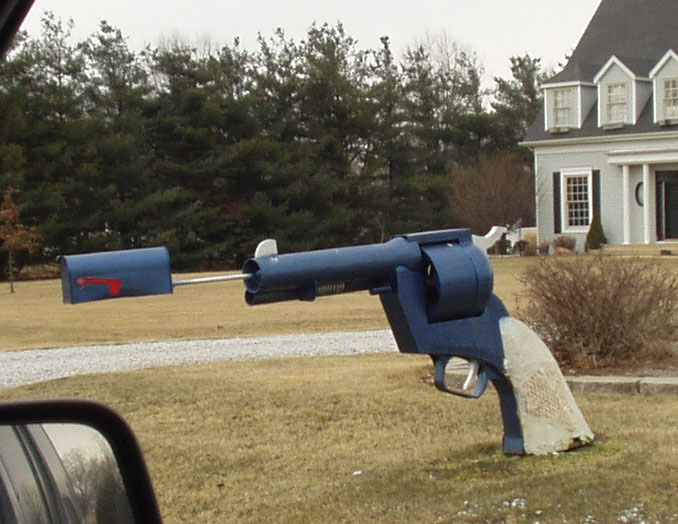 Pistola afuera de una casa de la cual sale el buzón de correo 