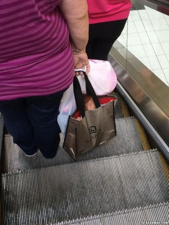mujer en las escaleras de un centro comercial con una niña dentro de una bolsa 