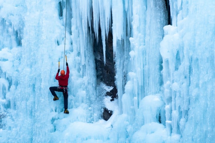 Persona escalando sobre una montaña con nieve 