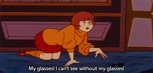 Gif de vilma de la caricatura de Scooby Doo buscando sus lentes en el suelo 