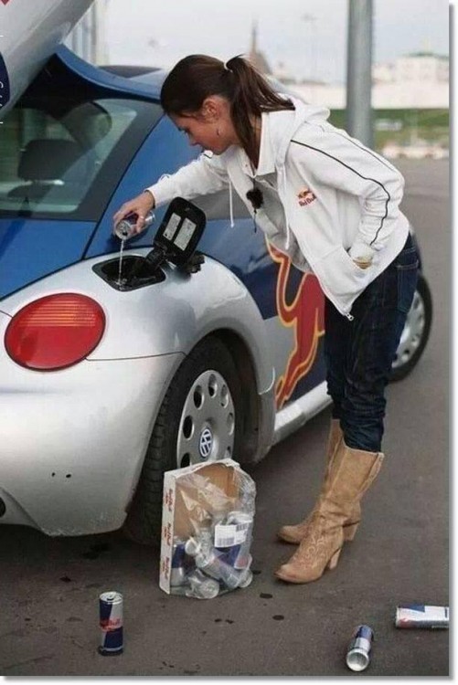 Mujer vertiendo un red bull en el tanque de gasolina de un coche 