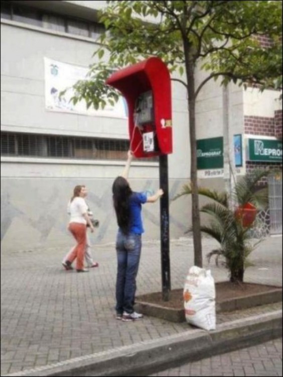 Chica intentando descolgar un teléfono demasiado alto