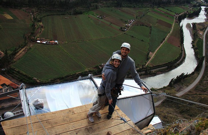 una pareja parada sobre una base madera al escalar una montaña 