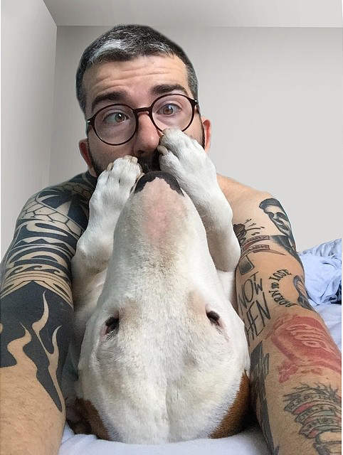 Selfie de un hombre con su perro sosteniendo su cara con sus patas 