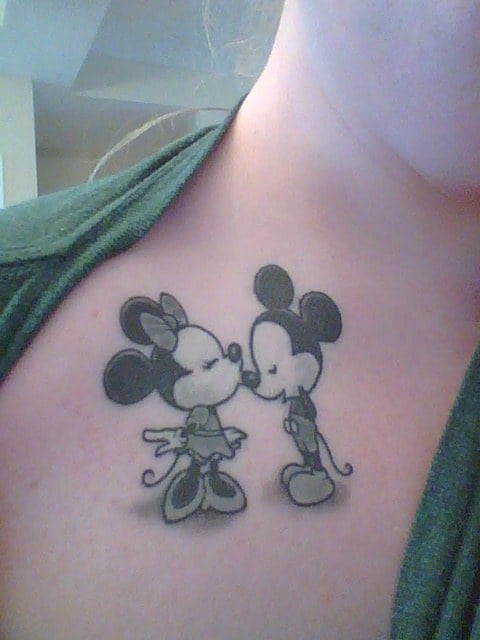 Tatuaje en el pecho de una persona de mickey mouse y minnie dándose un beso