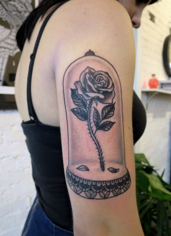 Tatuaje en el brazo de una chica con el diseño de la rosa que sale en la película "La bella y la bestia" 
