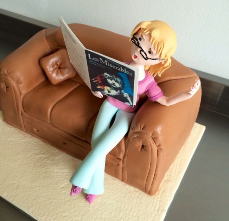 chica leyendo una revista sobre un pastel en forma de sofá 