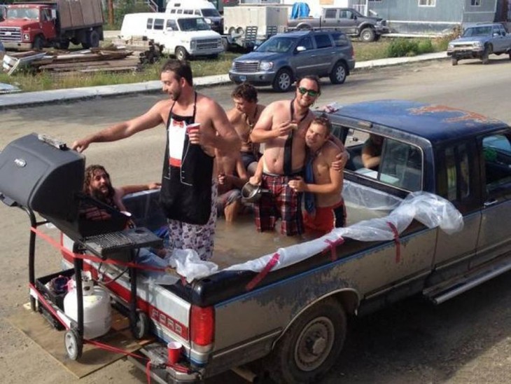 personas dentro de la cajuela de una camioneta llena de agua haciendo una carne asada 