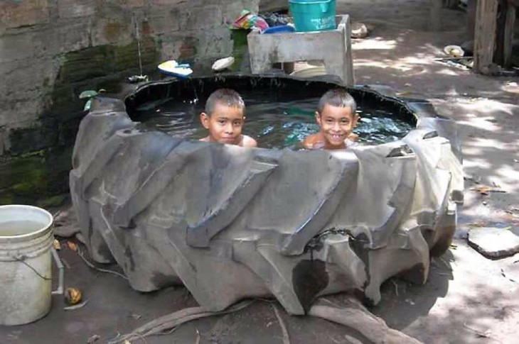 Niños dentro de una llanta enorme con agua dentro 