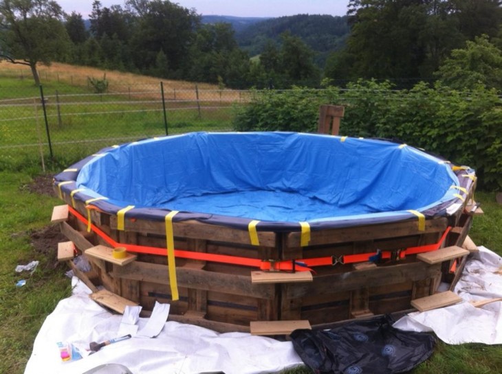 Procedimiento para crear una piscina de palets con una lona azul sobre ella 