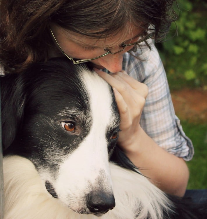 Chica abrazando a su perro con cara de tristeza