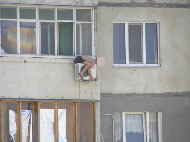 niño arreglando el aire acondicionado por fuera de la ventana