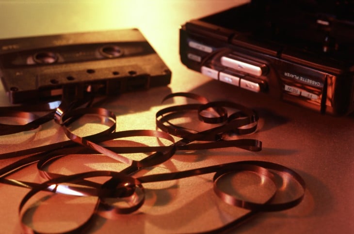 casette con la cinta de fuera a un lado de un grabadora de los años 90