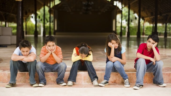 niños aburridos sentados en la banqueta