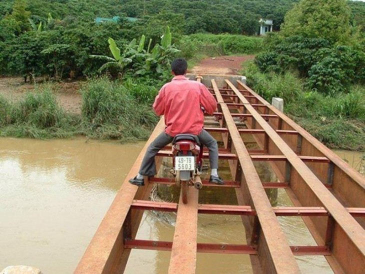 hombre de vietnam tratando de pasar por un lugar peligroso con su motocicleta